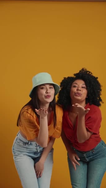 Piękne Wielonarodowe Kobiety Dmuchają Pocałunki Pokazują Gesty Przed Kamerą Żółtym — Wideo stockowe