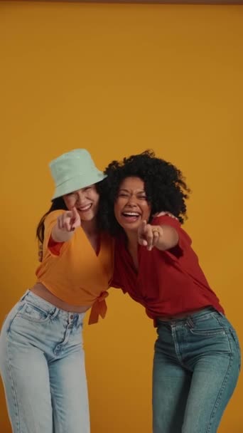 Laughing Multinational Women Hugging Pointing Fingers Camera Yellow Studio — Stock Video