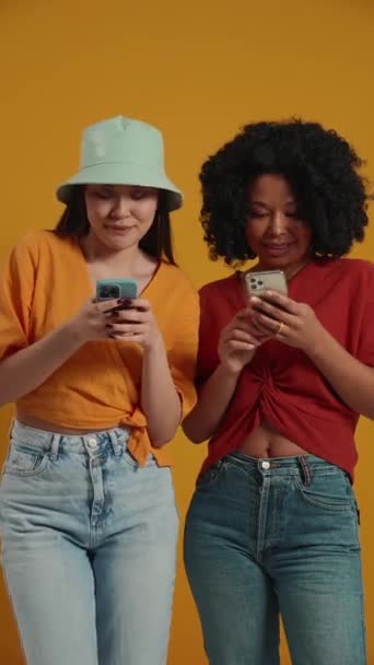 漂亮的跨国女性在黄色工作室里用手机发短信 — 图库视频影像