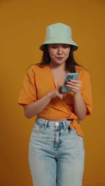 Happy Asian Woman Wearing Panama Hat Texting Mobile Yellow Studio — Stock Video