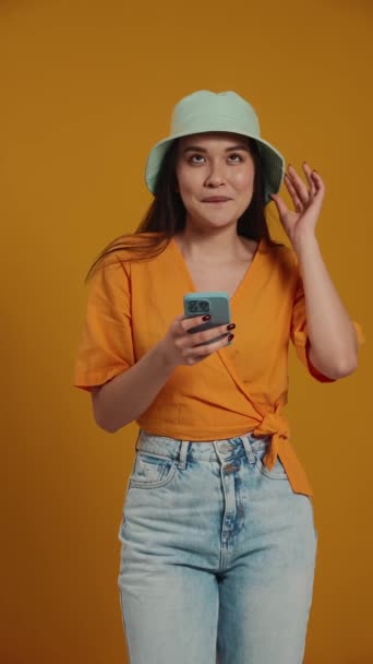 Pleased Asian Woman Wearing Panama Hat Texting Mobile Yellow Studio — Stock Video