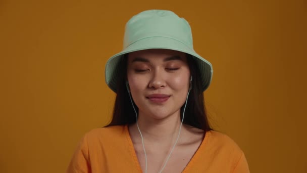 Красивая Азиатка Панамской Шляпе Слушает Музыку Наушниках Открывает Глаза Камеру — стоковое видео