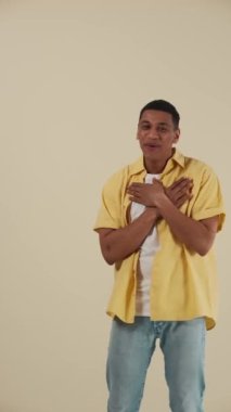 Bej rengi stüdyoda dans edip şarkı söyleyen Afrikalı pozitif bir genç.