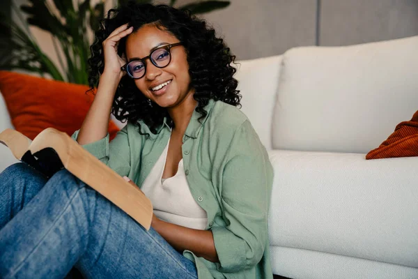 Young Cheerful African Woman Eyeglasses Reading Book While Sitting Home — Stock Photo, Image