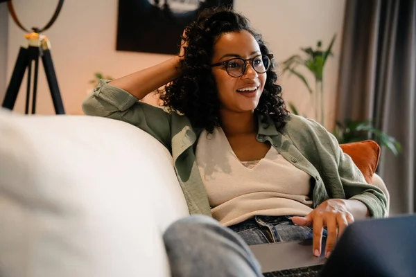 Cheerful Young African Woman Eyeglasses Using Laptop While Lying Sofa — Stock Photo, Image