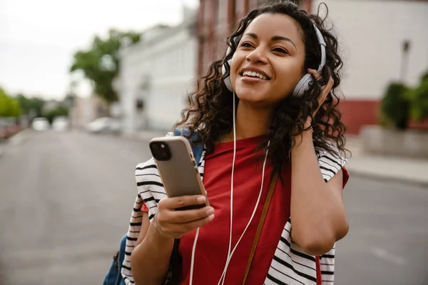 Joven Mujer Negra Auriculares Usando Teléfono Móvil Mientras Camina Aire —  Fotos de Stock