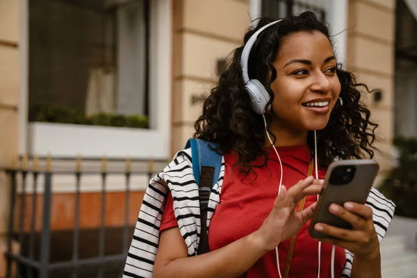 Joven Mujer Negra Con Auriculares Usando Teléfono Móvil Mientras Está —  Fotos de Stock