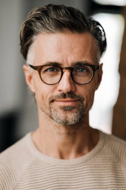 Gözlüklü, beyaz, orta yaşlı bir adamın kameraya bakıp içeri girmesi.