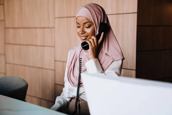 在接待处工作时打电话给穆斯林快乐的女商人 — 图库照片