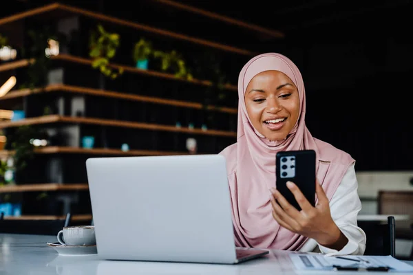 Młoda Muzułmanka Nosząca Chustę Głowie Pomocą Telefonu Komórkowego Podczas Pracy — Zdjęcie stockowe