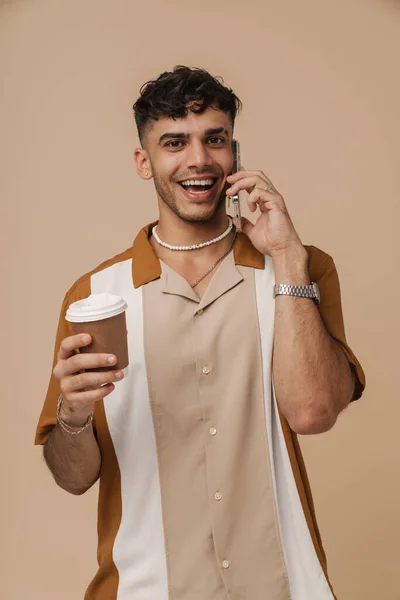 Mladý Pohledný Stylový Usmívající Muž Náhrdelníku Mluvící Telefon Drží Kávu — Stock fotografie