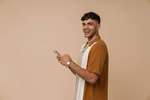 Mladý Pohledný Stylový Usměvavý Muž Náhrdelníku Drží Telefon Dívá Kameru — Stock fotografie