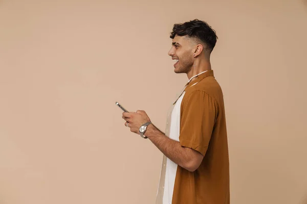 Mladý Pohledný Stylový Usměvavý Muž Náhrdelníku Drží Telefon Zatímco Stojí — Stock fotografie
