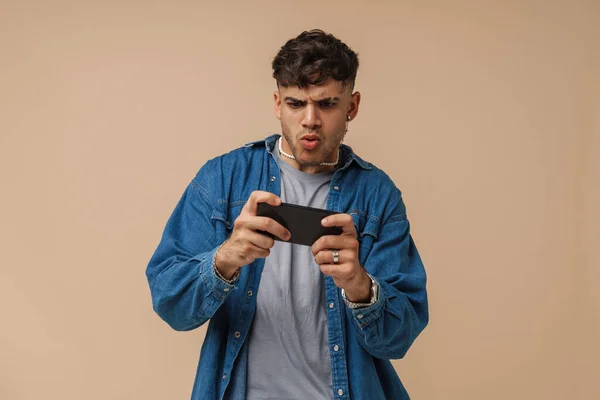 Молодой Красивый Стильный Заинтересованный Мужчина Сморщенными Губами Играющий Мобильную Игру — стоковое фото