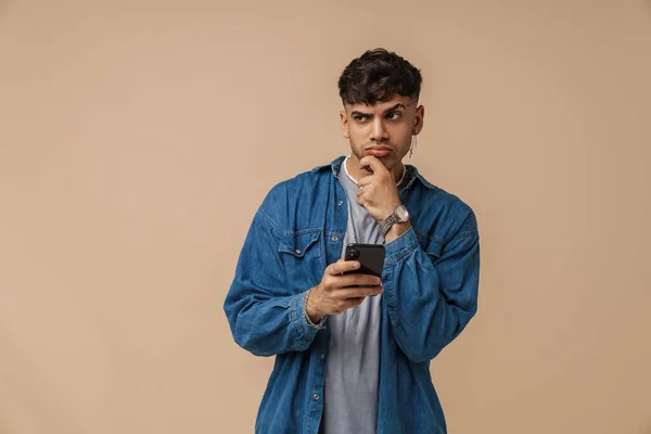 Brunett Ung Man Bär Skjorta Rynka Pannan Och Använda Mobiltelefon — Stockfoto
