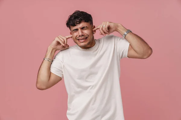 Μελαχρινή Νεαρός Άνδρας Γκρίνια Ενώ Συνδέοντας Αυτιά Του Απομονώνονται Ροζ — Φωτογραφία Αρχείου