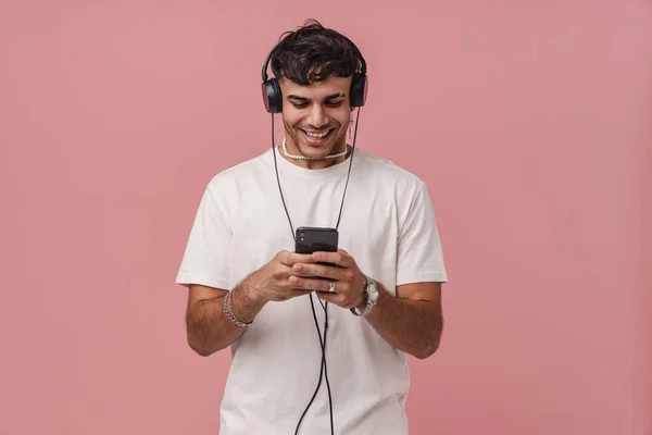 Brunetka Młody Człowiek Słuchawki Uśmiechnięty Podczas Korzystania Telefonu Komórkowego Izolowane — Zdjęcie stockowe
