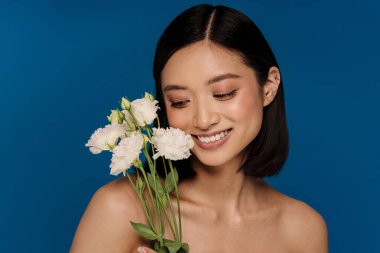 Genç, güzel, gülümseyen, beyaz çiçekli mutlu Asyalı bir kadının portresi.