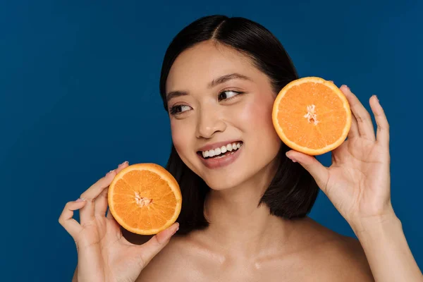 배경에 오렌지 토막을 바라보고 행복하게 미소짓고 아름다운 아시아 여인의 — 스톡 사진