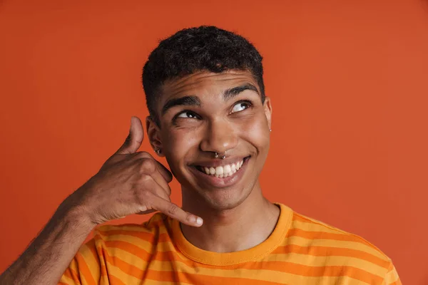 잘생긴 미소를 아프리카 남자의 손가락으로 핸드폰 시늉을 고립된 오렌지 — 스톡 사진
