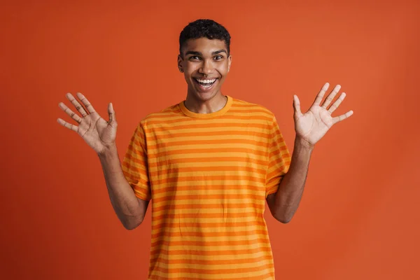 年轻英俊而热情的非洲男子 双手高举 张开嘴 站在孤立的橙色背景上看着相机 — 图库照片