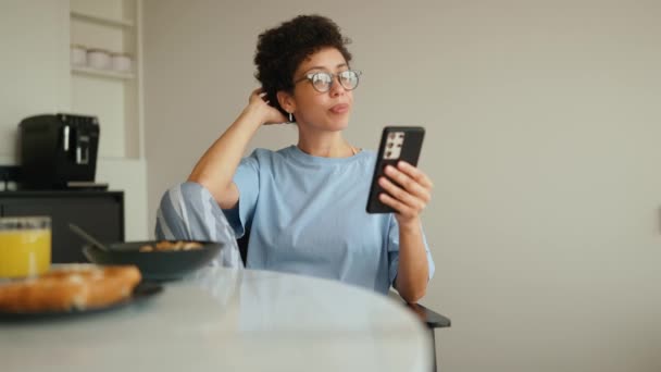 Concentrated Latin Curly Haired Woman Having Breakfast Typing Mobile Kitchen — Stock Video