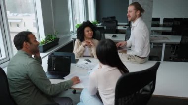 Neşeli çok uluslu meslektaşlar konferans odasında iş projelerini tartıştılar.