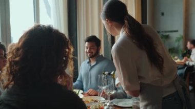 Güzel garson, kafeteryada doğum gününü kutlayan arkadaşlarına şarap dolduruyor. Parti konsepti