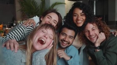 Kafede doğum günü kutlaması için kameraya poz veren neşeli çoklu etnik arkadaşlar.