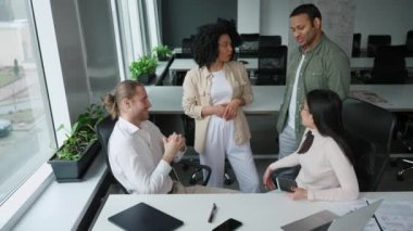 Neşeli çok uluslu meslektaşlar iş geliştirme konusunu ofisteki konferans odasında tartıştılar.