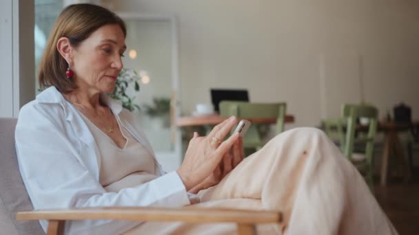 Kafede Telefonda Yazan Beyaz Gömlekli Düşünceli Yaşlı Kadın — Stok video