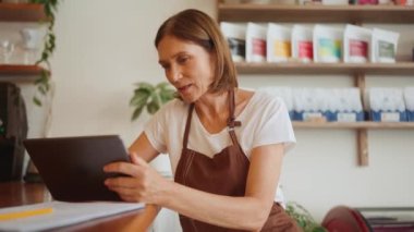 Kafedeki dijital tabletten konuşan yakışıklı, olgun bir barmen kadın.