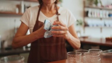 Kafede tezgahın arkasında bardakları silen kadın.