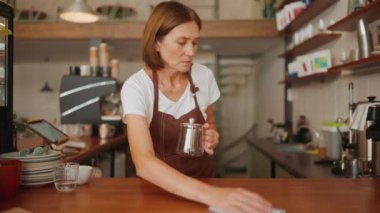 Kafede tezgahın arkasında ciddi bir kadın barista siliyormuş.