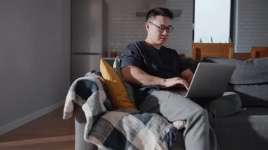 Evde dizüstü bilgisayarda çalışan kendine güvenen Asyalı gözlüklü yatırımcı