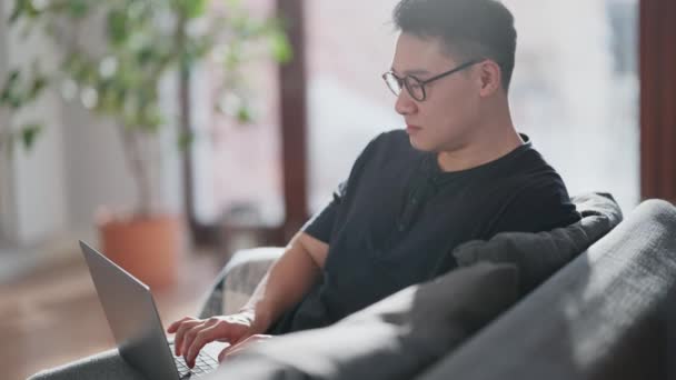 Pensive Aziatische Man Bril Typen Laptop Thuis — Stockvideo