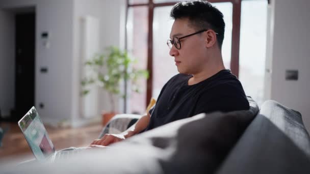 Concentrated Asian Man Eyeglasses Typing Laptop Home — Stock Video