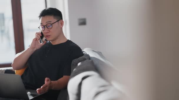 Seriöser Asiatischer Mann Mit Brille Spricht Handy Und Arbeitet Hause — Stockvideo