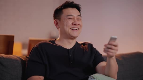 Nevető Ázsiai Férfi Néz Otthon Kanapén — Stock videók