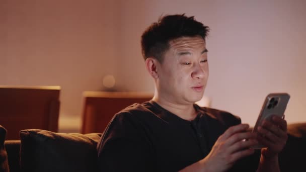 Ευτυχισμένος Ασιάτης Που Στέλνει Μηνύματα Στο Smartphone Του Στο Κρεβάτι — Αρχείο Βίντεο