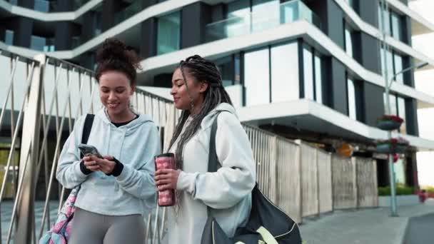Dwie Wielonarodowe Szczęśliwe Kobiety Patrzące Telefon Rozmawiające Zewnątrz Treningu Działalność — Wideo stockowe
