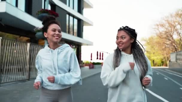 2人の笑顔の多国籍女性が屋外を走る スポーツ活動 アクティブなライフスタイル — ストック動画