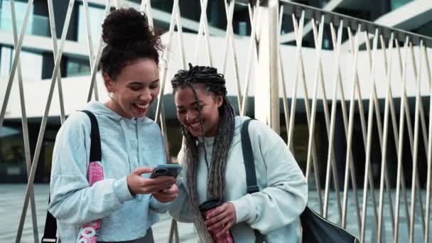 两个笑着看手机和锻炼后在外面说话的跨国女性 体育活动 积极的生活方式 — 图库视频影像