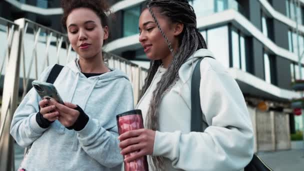 Två Självsäkra Multinationella Kvinnor Tittar Telefonen Och Pratar Utanför Efter — Stockvideo