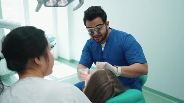 Pewny Siebie Indyjski Dentysta Okularach Sprawdza Jamy Ustnej Pacjenta Lustrem — Wideo stockowe