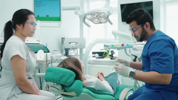 病院でミラーで患者の口腔を検査する幸せなインドの歯科医の男 歯医者の予約 — ストック動画