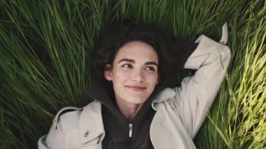 Sahada yatan bej renkli trençkotlu güzel kız.