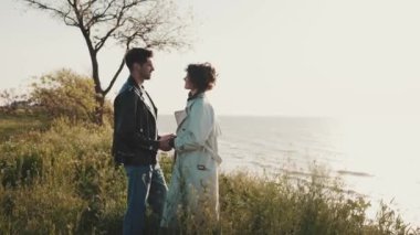 Denizin kenarında durup el ele tutuşan sevimli bir çift.