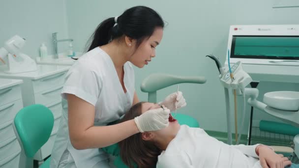 アジアの女性歯科医は 病院で鏡で患者の口腔をチェック 医者の予約 — ストック動画