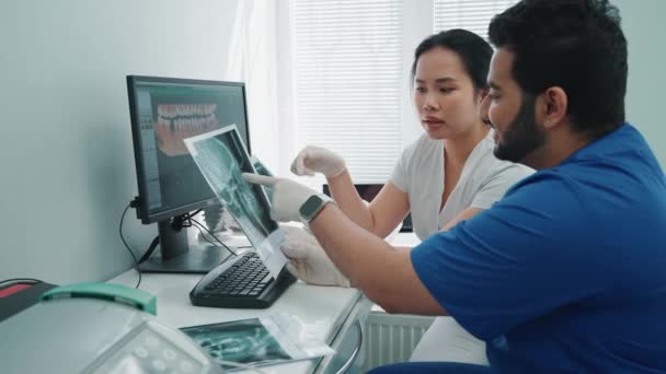 Przystojni Indyjscy Azjatyccy Dentyści Omawiają Panoramiczny Obraz Pacjentów Jamy Ustnej — Wideo stockowe